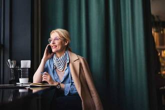 nicely dressed business woman talking on the phone in a cafe