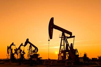 oil derricks in field at sunset