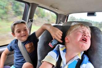 older brother annoying his younger sibling while in the car