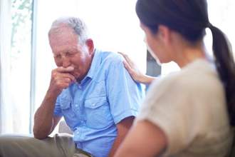 older gentleman grieving while a family member tries to comfort him