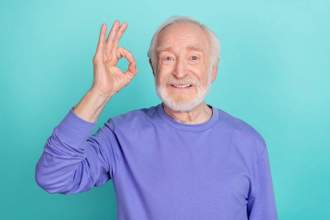 older gentleman holding his hand up in the okay sign while smiling at the camera