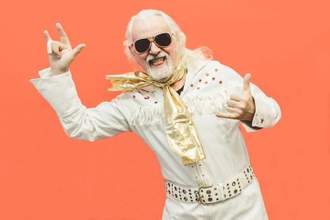 older gentleman wearing an elvis outfit while looking into the camera