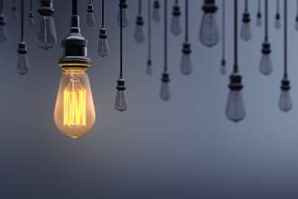 one lit lightbulb surrounded by many unlit ones