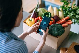 over the shoulder view of woman purchasing groceries with her phone