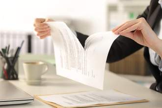 person holding a document over their desk ripping it apart