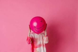 person holding a smiling balloon in front of their face