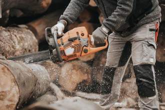 person using a chainsaw to cut wood