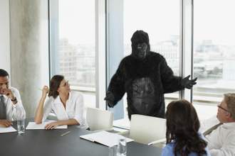 person wearing a gorilla suit giving a talk within an official office setting