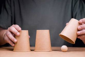 playing the shell game with a wood ball and cups
