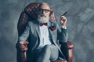 rich man sitting in leather chair with cigar and whiskey