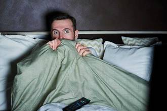 scared man watching horror movies at night