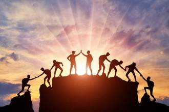 silhouette of climbers who climbed to the top of the mountain thanks to teamwork