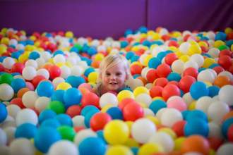 small child sitting in a huge ball pit