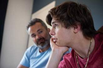 teenage boy looking into the distance while talking with his father
