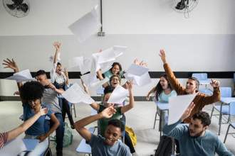 teenage students throwing paper in the air excited for the end of school