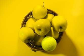 tennis ball in a basket of green apples