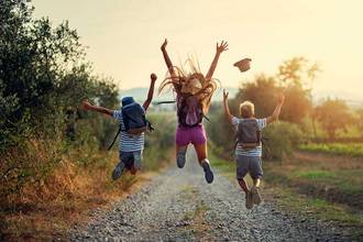 three children on a hike jumping for joy