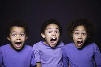 three children wearing purple t-shirts looking into the camera and screaming