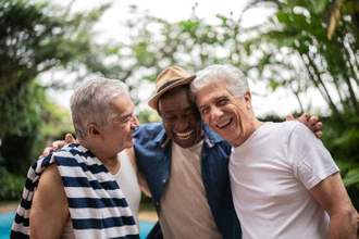 three men smiling and having a good time by the pool