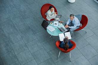 three people sitting in chairs around small table