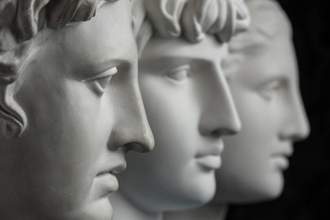 three statue heads looking to the right with no emotion