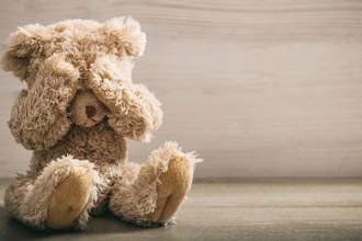 tiny teddy bear holding its paws over its eyes upset