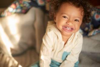 tiny toddler smiling up at the camera