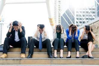 tired colleagues sitting on the city steps with their hands holding their heads