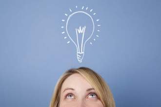 top half of womans face peering up at the drawing of a bright light bulb