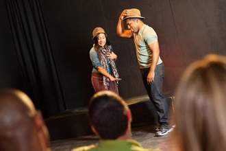 two actors ad-libing on the small stage in front of an audience