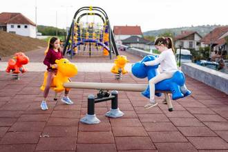 two children playing on a playground seesaw together