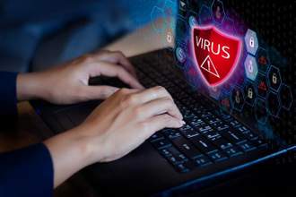 two hands typing on their computer as a red virus pop-up shows up on the screen
