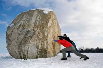 two men trying to push a huge boulder