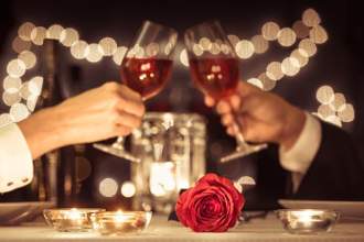 two people having a romantic dinner clinking their wine glasses together
