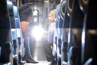 two people smiling and shaking hands after meeting on a bus