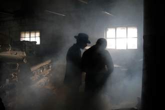 two shadowy figures in smoky storeroom