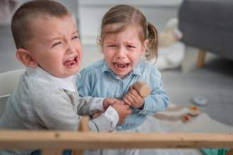 two toddlers angry and fighting over toys