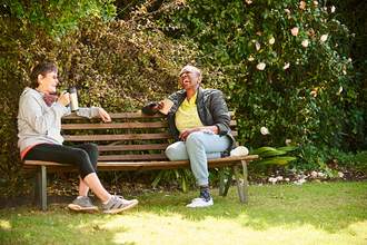 two women laughing on park bench
