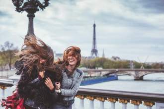 two young women walking through the city while the wind is tousling their hair