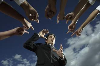 various hands pointing accusingly at a business man
