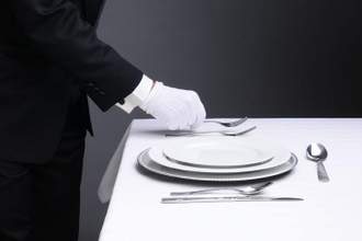 waiter setting formal dinner table