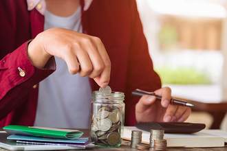woman budgeting and using jar of coins