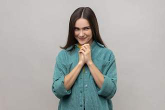 woman clasping her hands tightly holding a facial expression that seems conniving