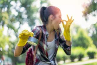 woman cleaning up smelly garbage looking disgusted