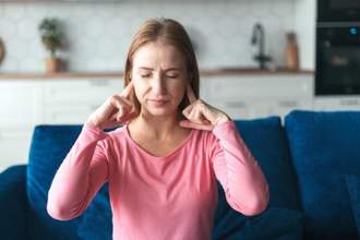 woman closing her eyes and holding fingers to ears