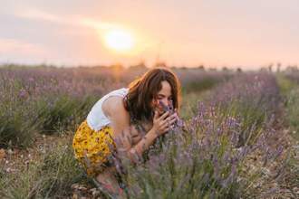 woman crouching down in the fields and smelling the lavender