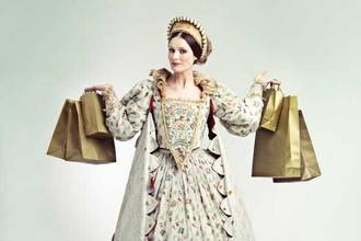woman dressed in royal regalia holding up a number of shopping bags