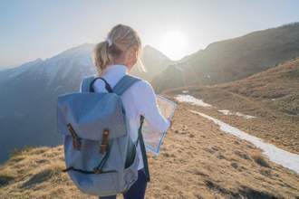 woman going on a hike in the mountains looking at her map