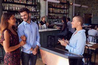 woman greets couple at front of restaurant