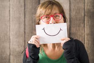 woman holding paper smile over face